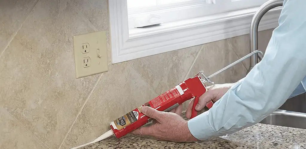Handyman applying caulk along a kitchen backsplash and countertop seam in Tulsa, OK