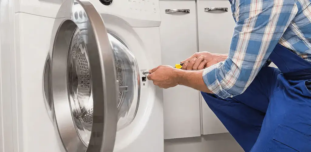 Handyman repairing a clothes dryer and checking electrical connections in Tulsa, OK