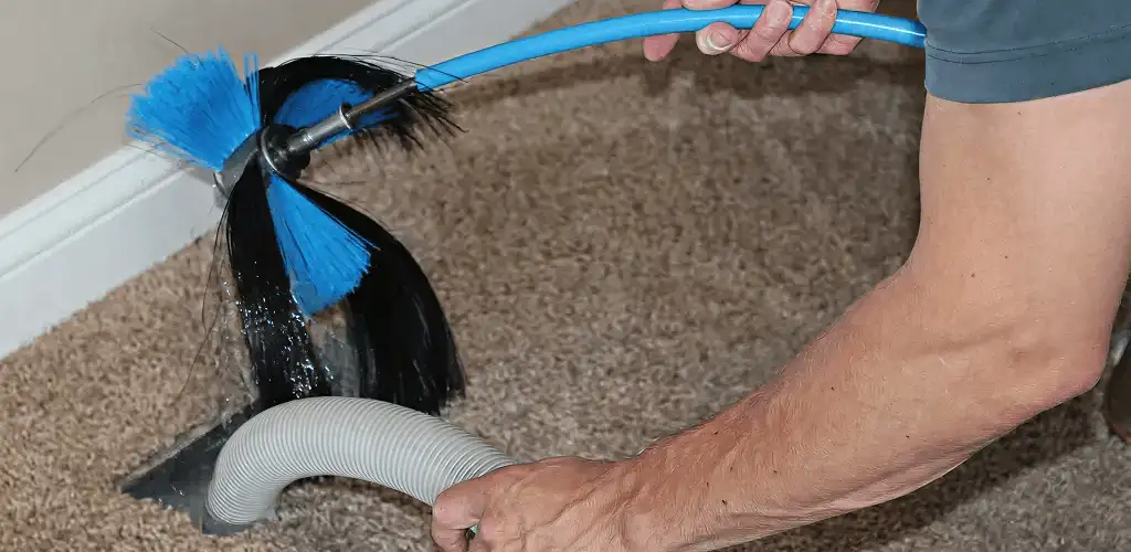 Dryer vent cleaning technician brushing lint from a vent line in Tulsa, OK