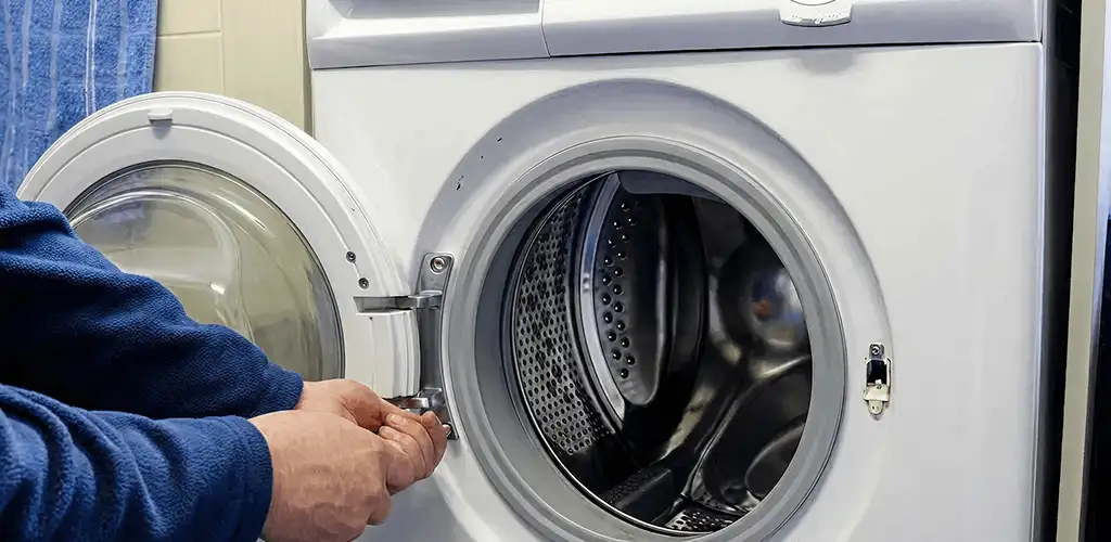 Washing machine repair handyman checking a front-load washer door and latch in Tulsa, OK