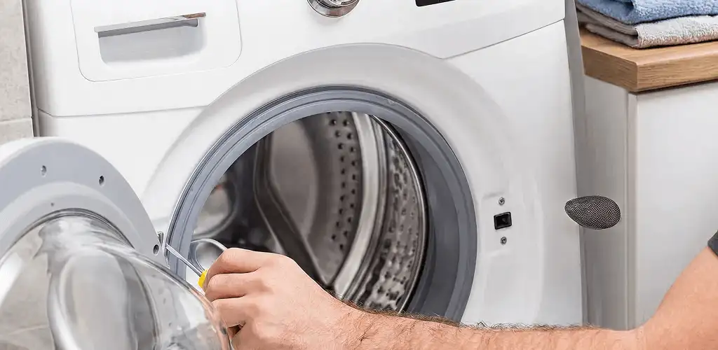 Handyman repairing a front-load washing machine and inspecting the drum in Tulsa, OK
