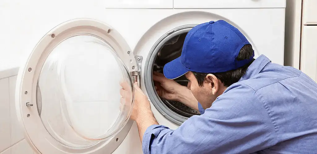 Washing machine repair handyman inspecting a front-load washer drum in Tulsa, OK