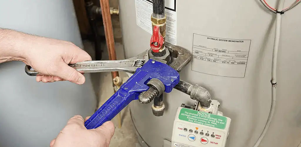 Water heater repair technician tightening the shutoff valve and supply line in Tulsa, OK
